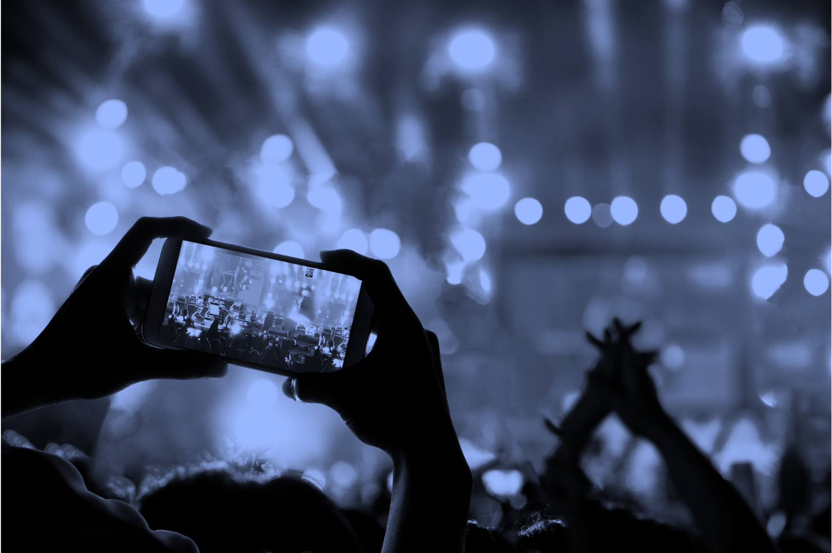 A person taking a picture of a concert with their phone.